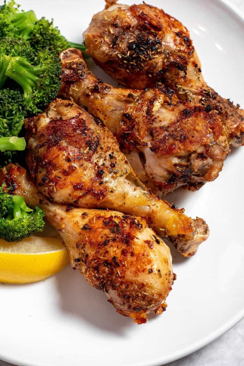 air fryer roasted chicken legs on a plate with broccoli
