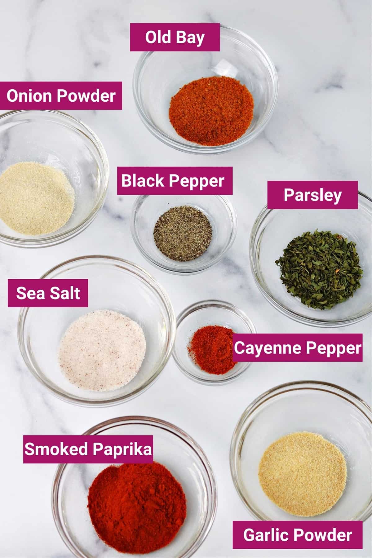 ingredients in cajun seasoning (old bay, onion powder, parsley, black pepper, sea salt, cayenne pepper, smoked paprika, and garlic powder) in separate bowls