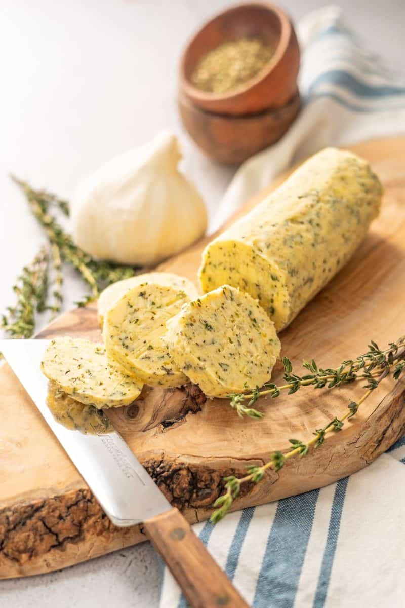 herb butter for steak with rosemary and garlic bulbs on a cutting board