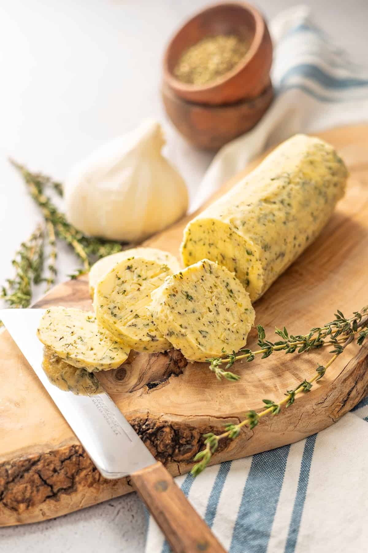 herb butter for steak with rosemary and garlic bulbs on a cutting board