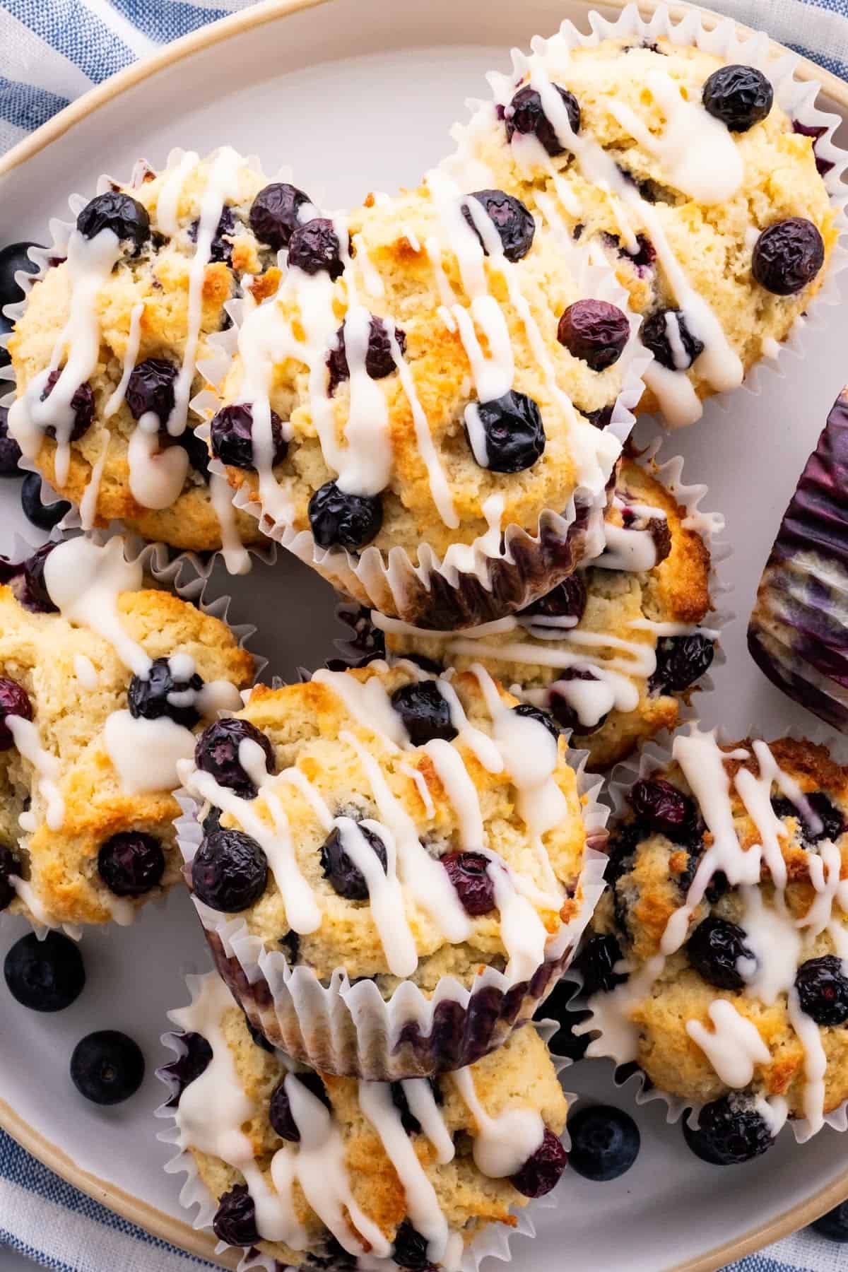 a close up of almond flour blueberry muffins with sour cream on a plate with keto glaze