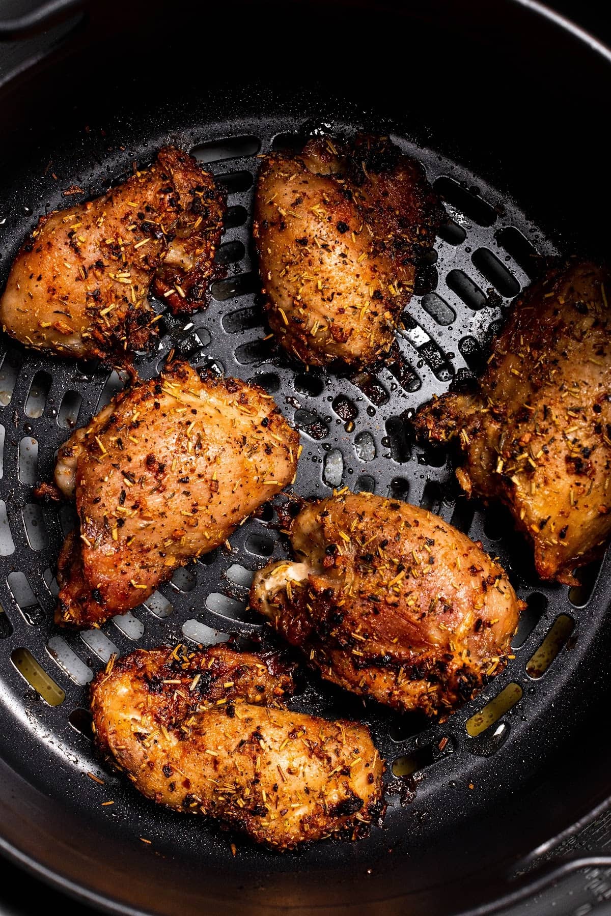 cooked boneless and skinless chicken thighs in the Ninja Foodi air fryer basket