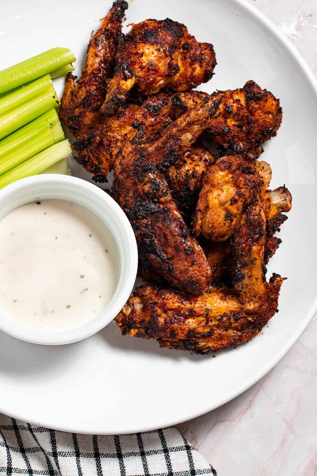 cooked cajun chicken wings on a plate with celery and dip