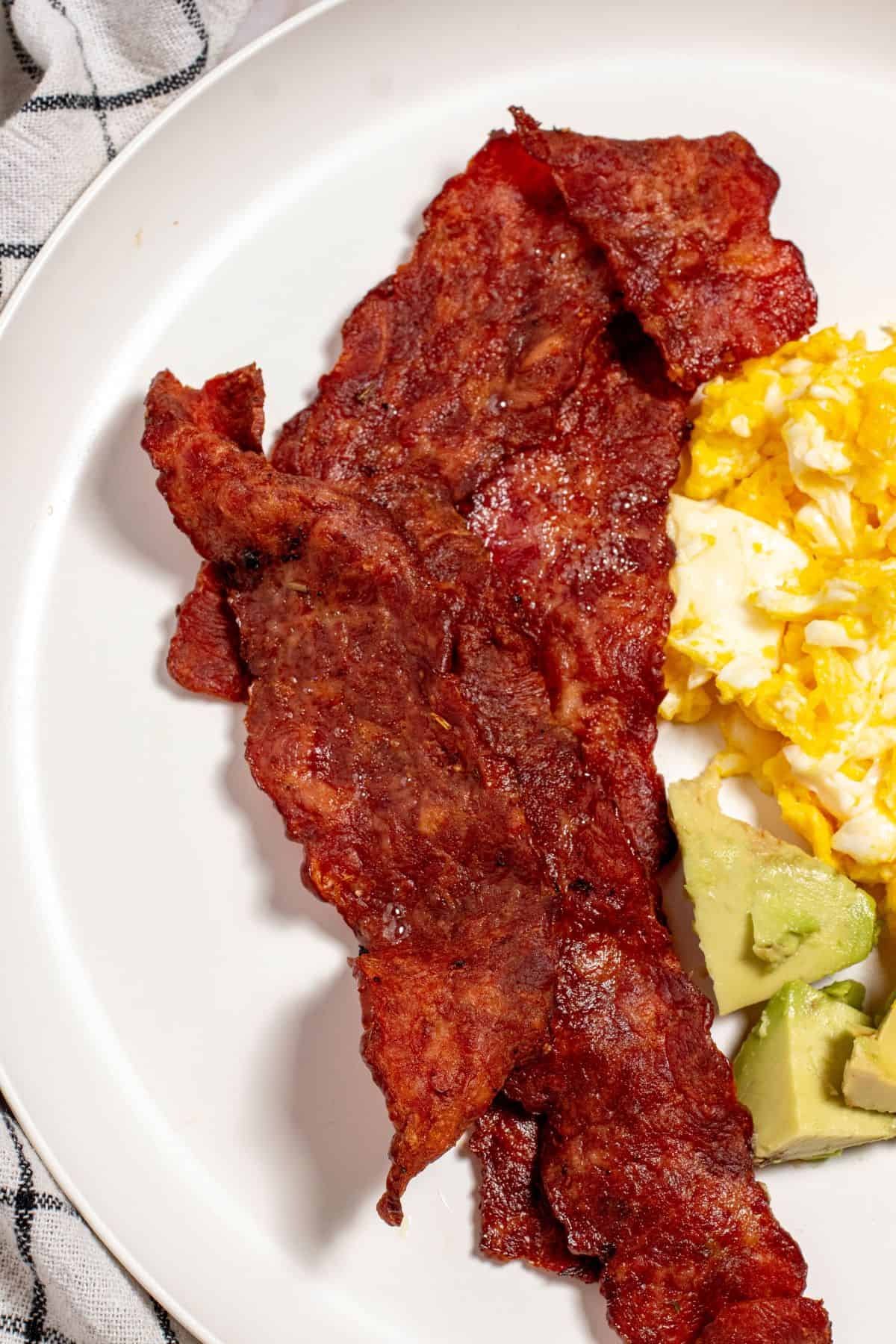 plated air fried turkey bacon with fried egg and avocado slices