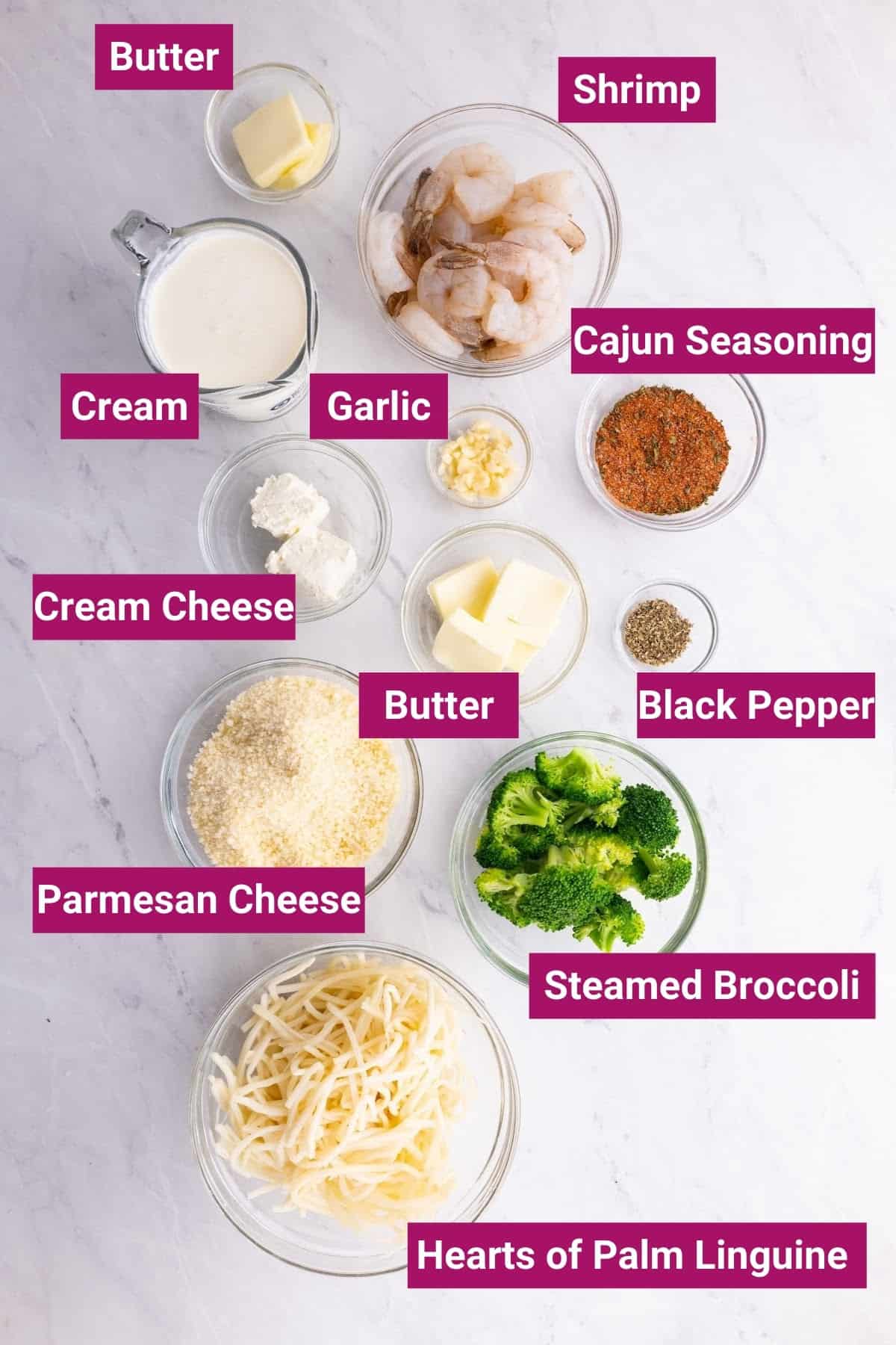 ingredients to make cajun shrimp alfredo pasta: heavy cream, cream cheese, parmesan cheese, cajun seasoning, shrimp, low-carb pasta, butter, garlic and broccoli in separate bowls