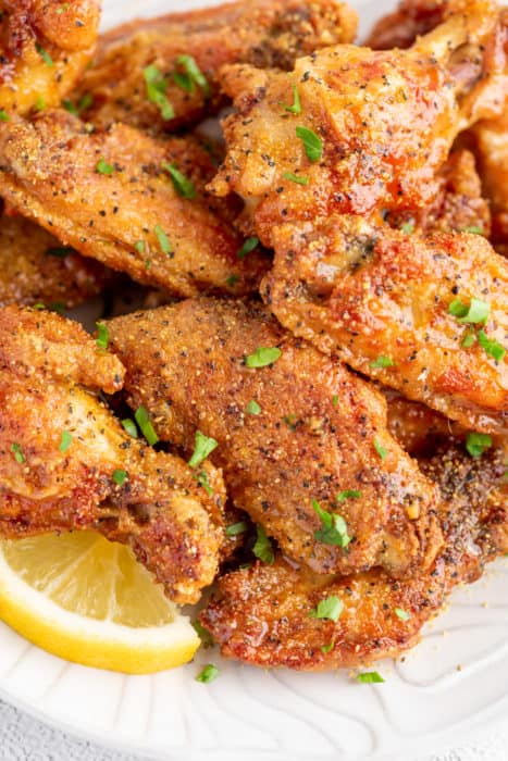 crispy lemon pepper wings topped with parsley sprigs on a plate