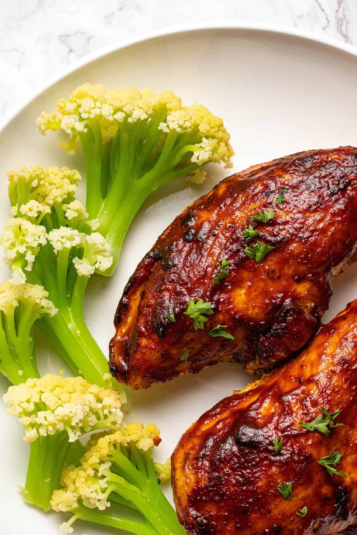 air fryer bbq chicken breasts on a plate with caulilini