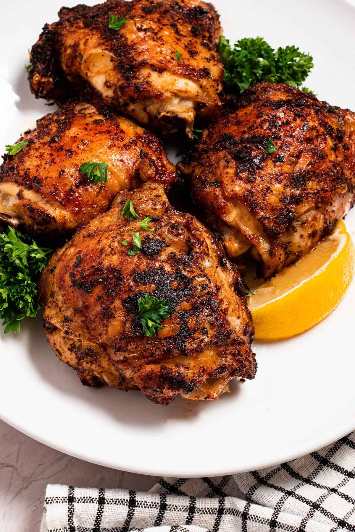 air fryer cajun chicken thighs on a plate with a lemon wedge