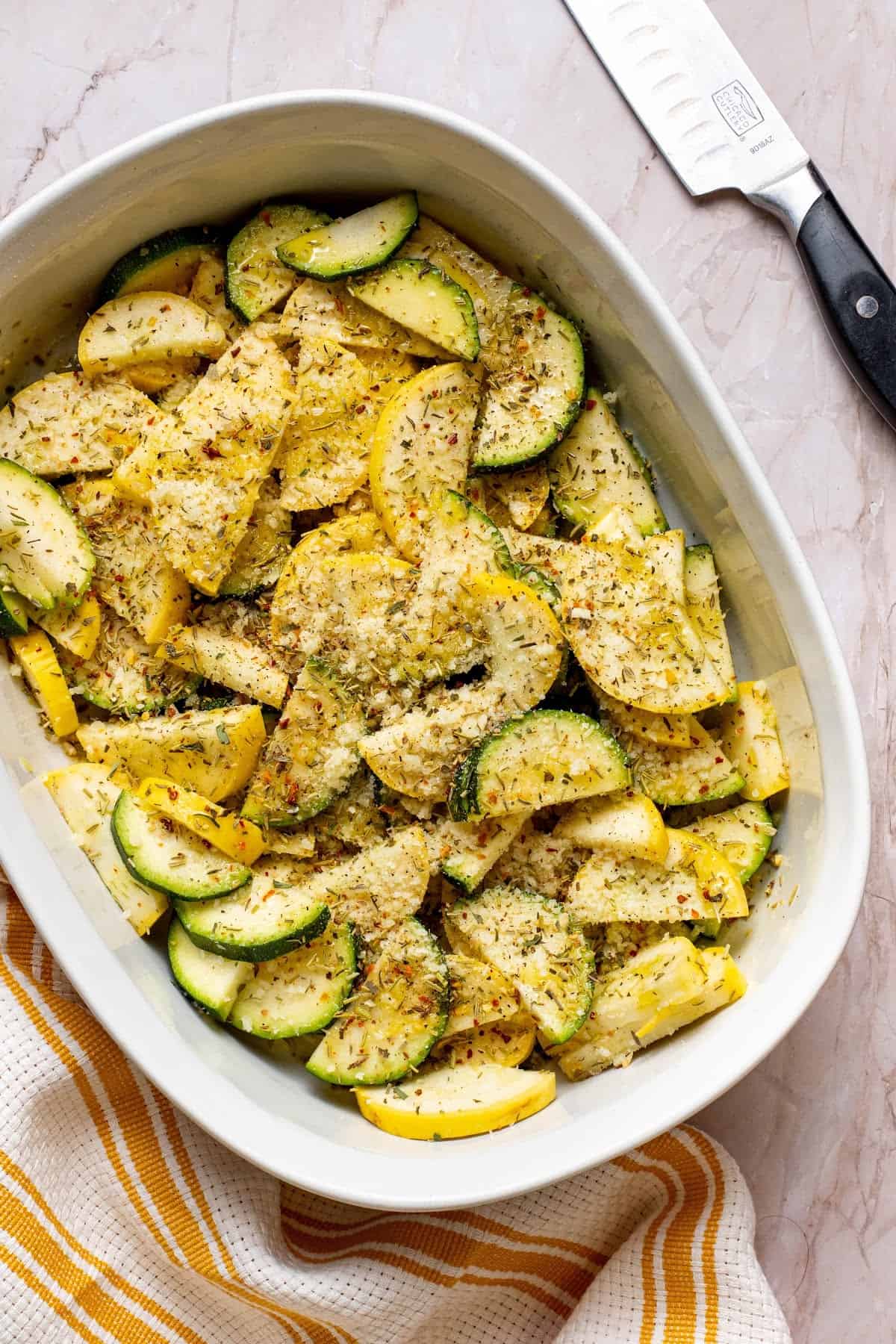 chopped yellow squash and zucchini squash in a bowl with Parmesan Cheese and seasoning