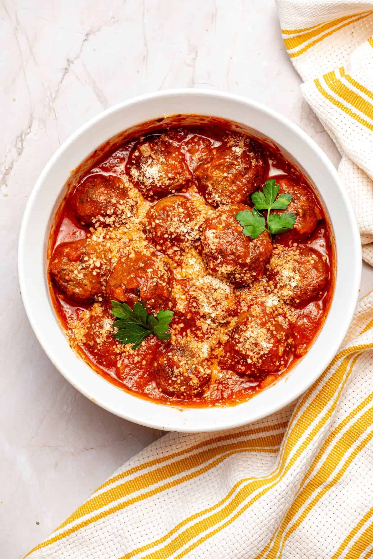 Air Fryer Frozen Meatballs with marinara sauce topped with parsley and parmesan cheese on a large bowl