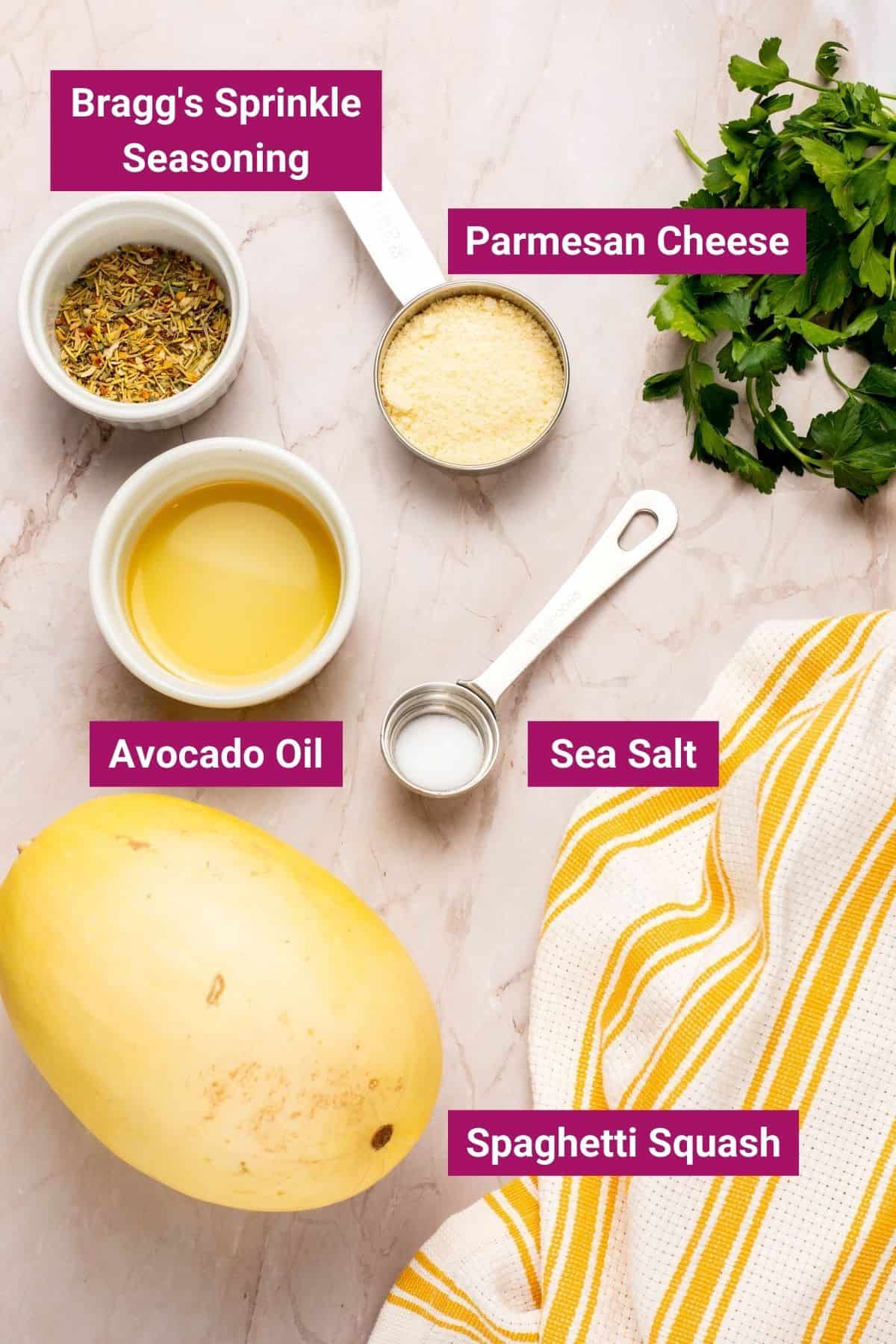 ingredients needed to make air fryer spaghetti squash like parmesan cheese, seasoning, avocado oil, sea salt in separate containers and a spaghetti squash