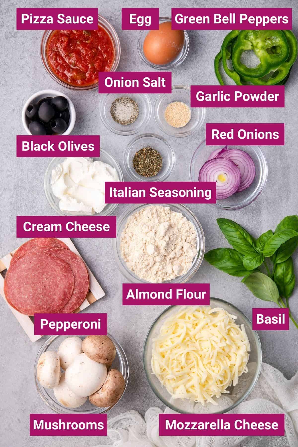 ingredients of Fathead Pizza Dough (keto pizza crust) in separate bowls: pizza sauce, egg, green bell peppers, onion salt, garlic powder, red onions, black olives, cream cheese, pepperoni, almond flour, Italian seasoning, shredded mozzarella, mushrooms, and basil