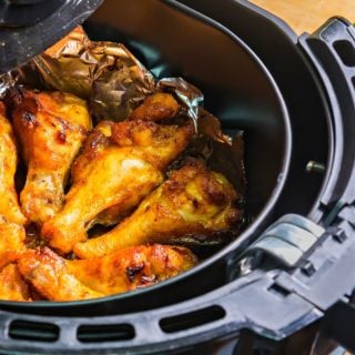 chicken wings sitting on aluminum foil in an air fryer basket