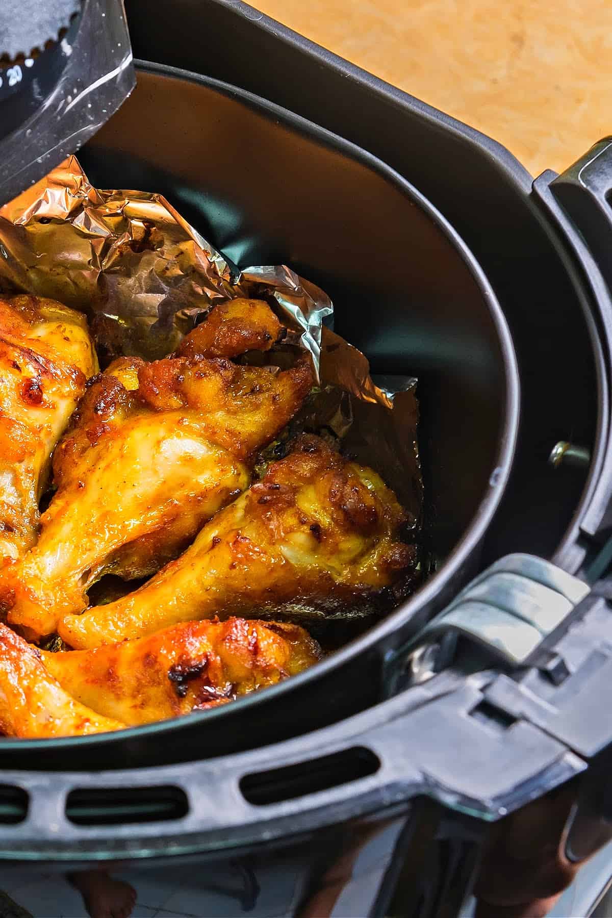 chicken wings sitting on aluminum foil in an air fryer basket