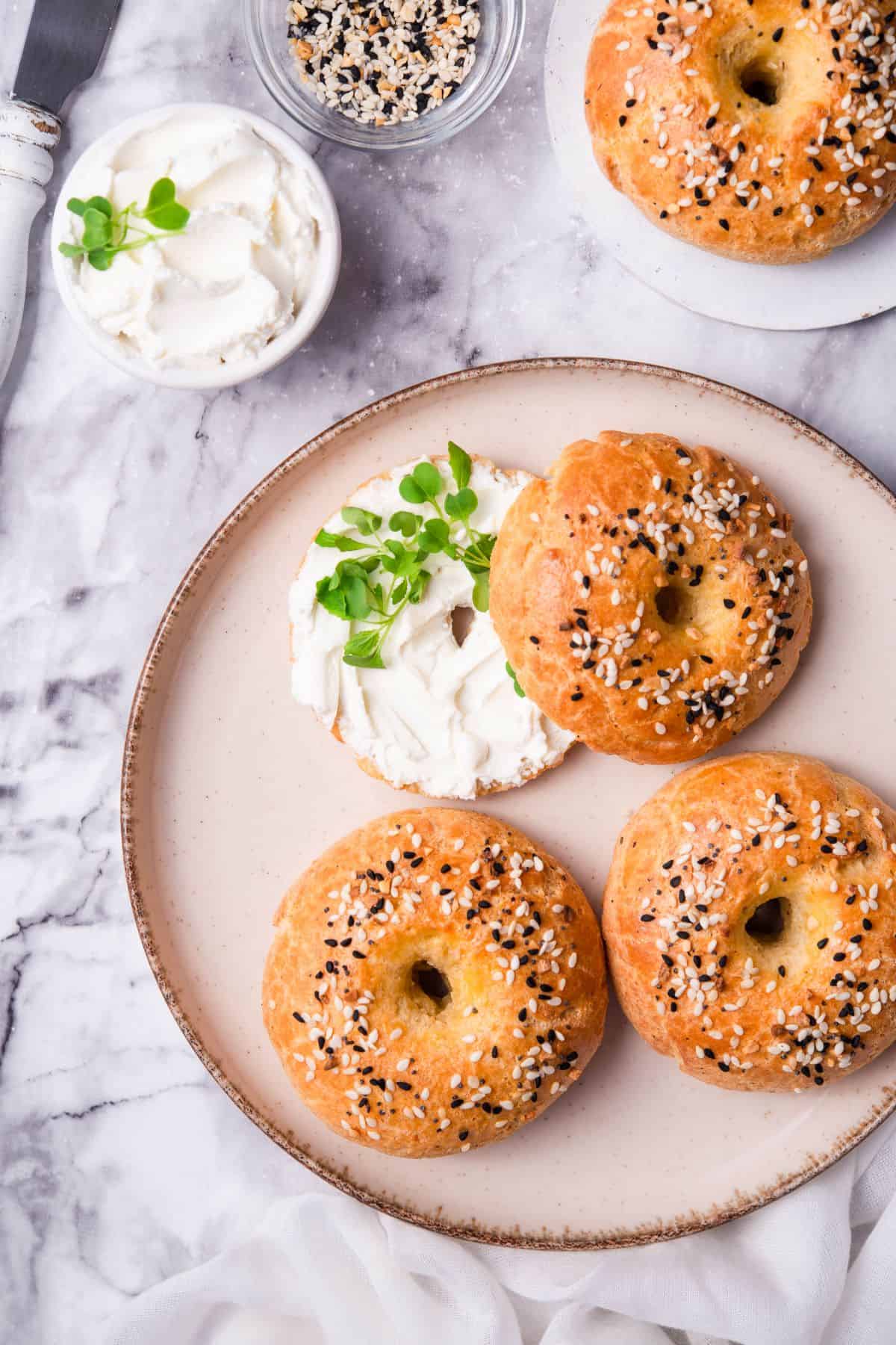 3 pieces of keto bagels on a large plate with cream cheese and chives