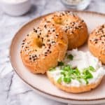 three keto bagels on a plate with cream cheese and chives