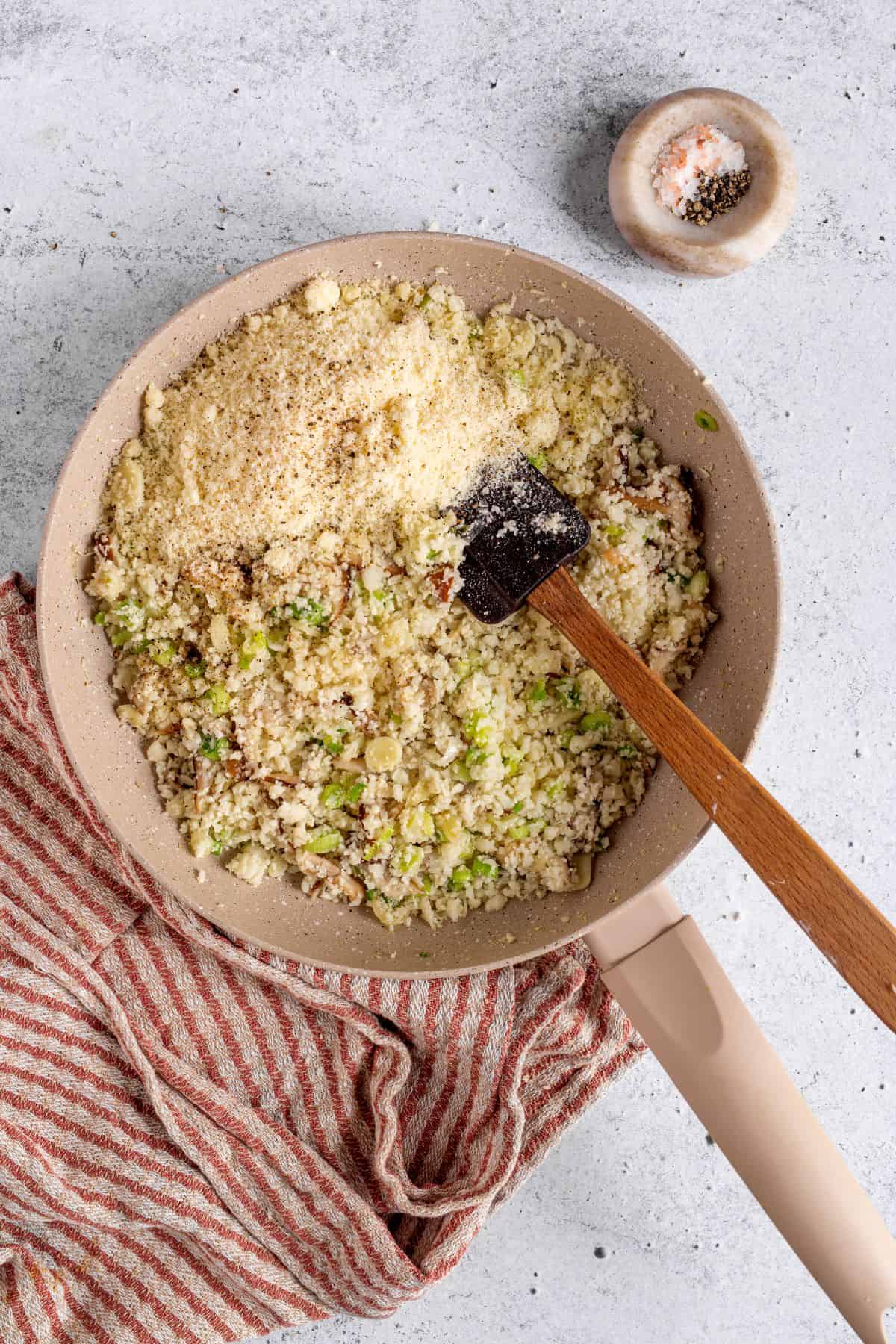 mixing parmesan cheese with riced cauliflower and other ingredients