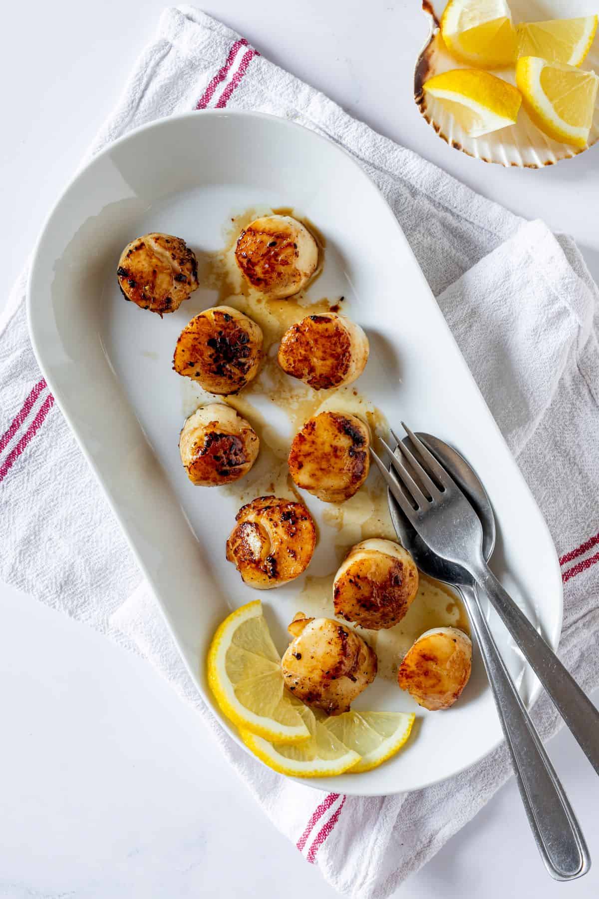 plated Seared Scallops with lemon beside spoon and fork