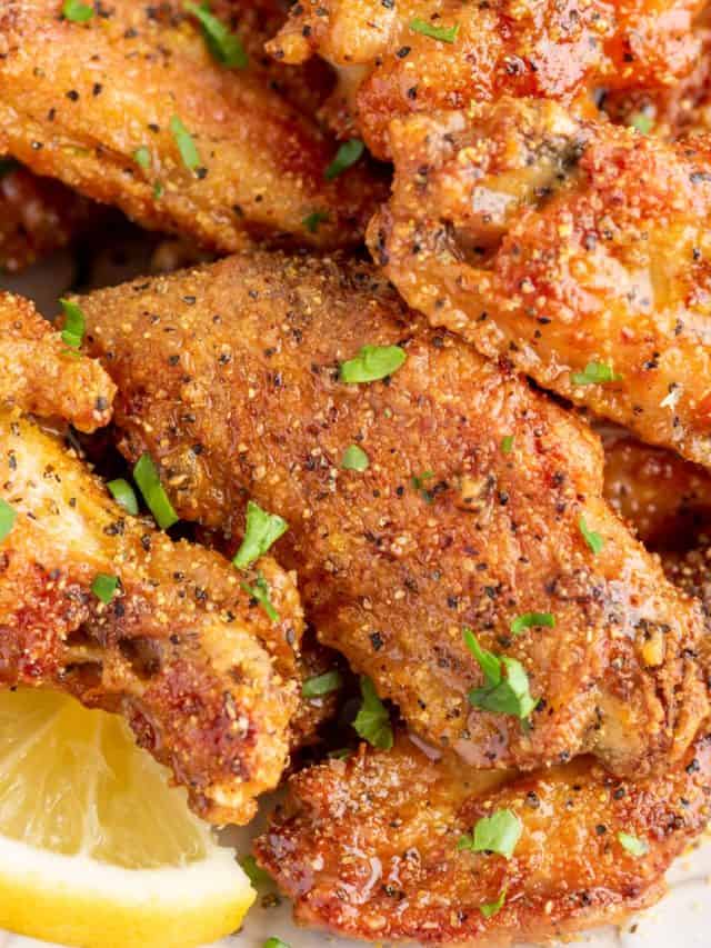 lemon pepper wings on a plate with a slice of lemon