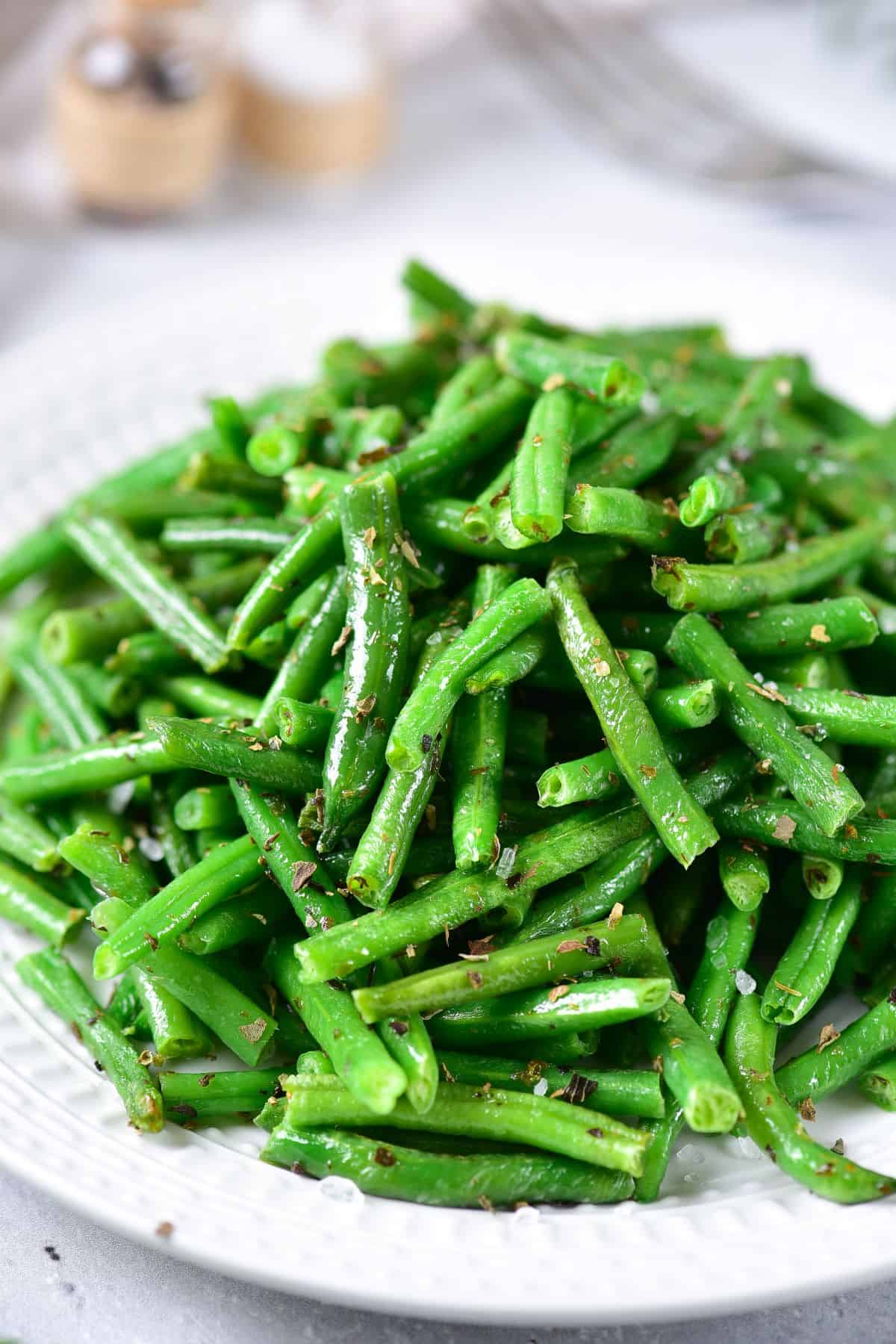 cooked Air Fryer Frozen Green Beans with herbs and seasonings on a plate