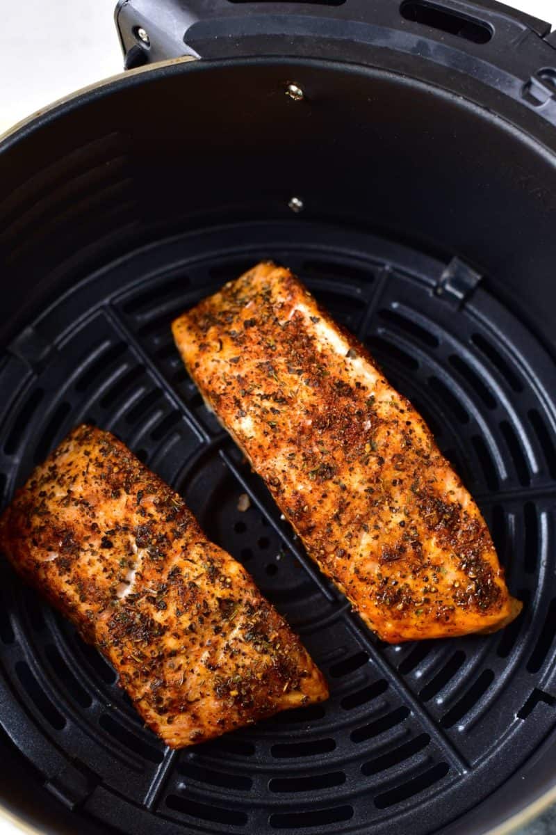 two pieces of cooked salmon filets in an air fryer basket
