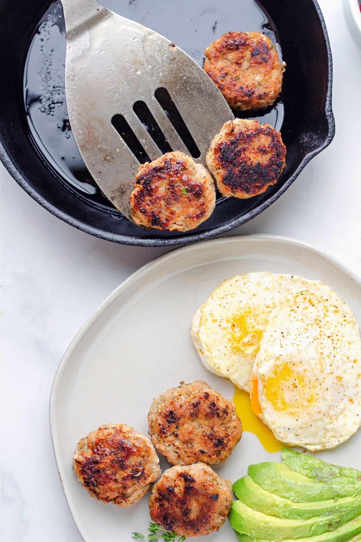 cooked chicken breakfast sausage in a cast iron skillet and a plate of chicken sausage with fried eggs and avocado