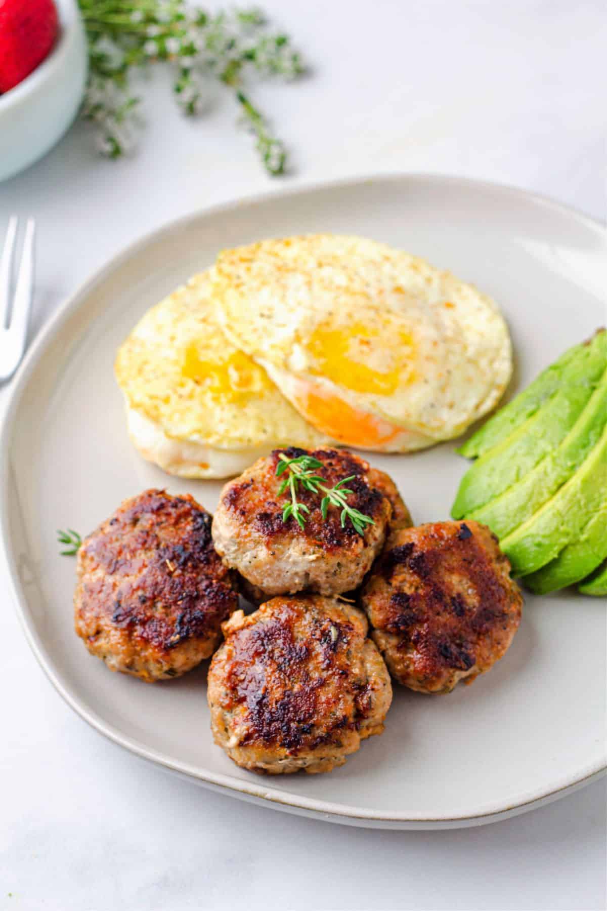 Chicken breakfast Sausages with fried eggs and avocado on the side