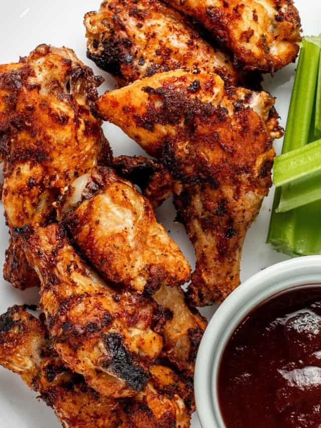 frozen wings cooked in an air fryer on a plate with celery and bbq sauce