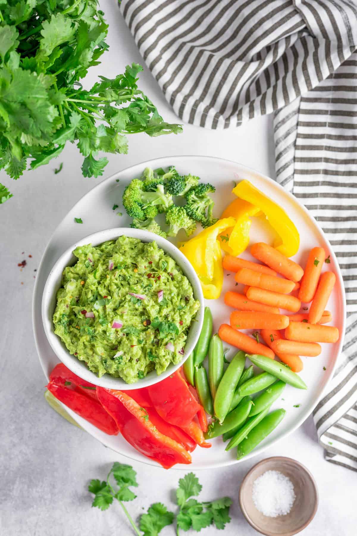 Guacamole in a bowl beside a vegetable snack plate