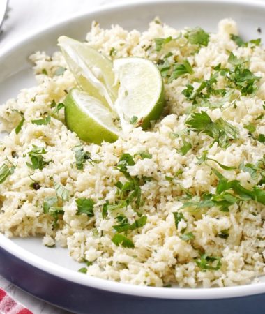 cilantro lime cauliflower rice in a bowl with lime wedges