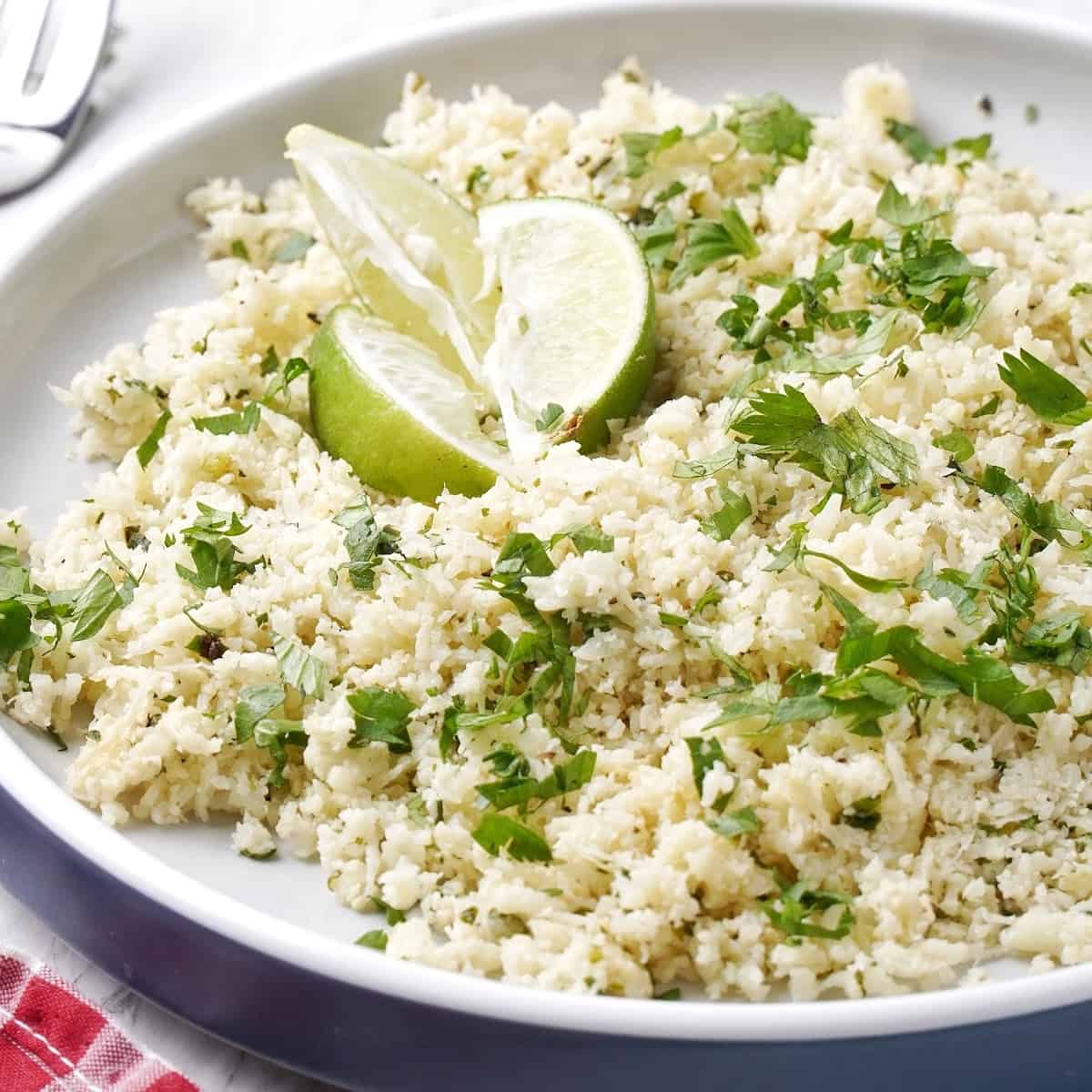 cilantro lime cauliflower rice in a bowl with lime wedges