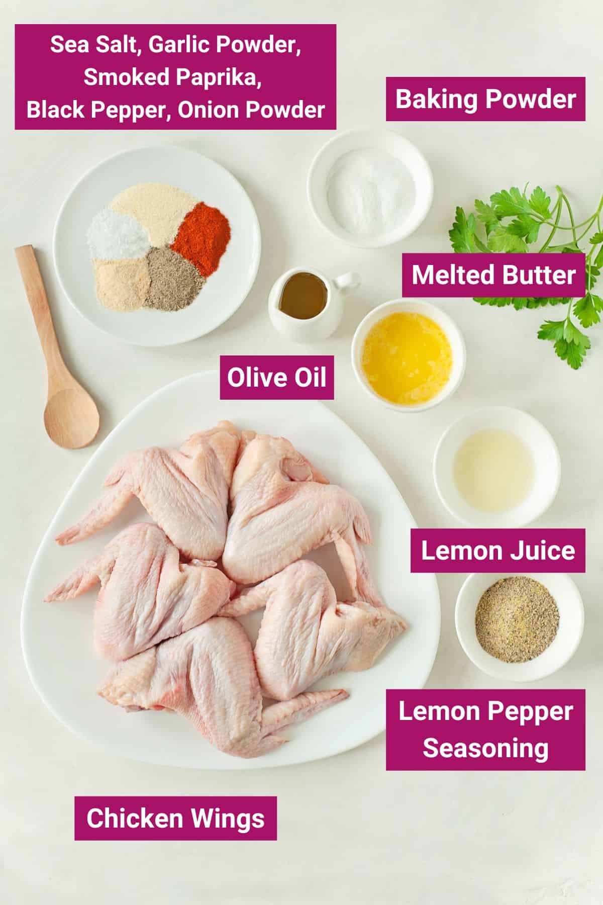 different spices, baking powder, melted butter, olive oil, lemon pepper seasoning, lemon juice and chicken wings on separate containers