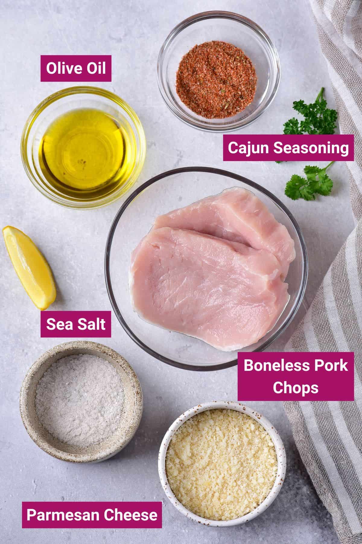 ingredients needed to make golden brown air fryer pork chops like cajun seasoning, olive oil, boneless pork chops, parmesan cheese, salt in separate bowls