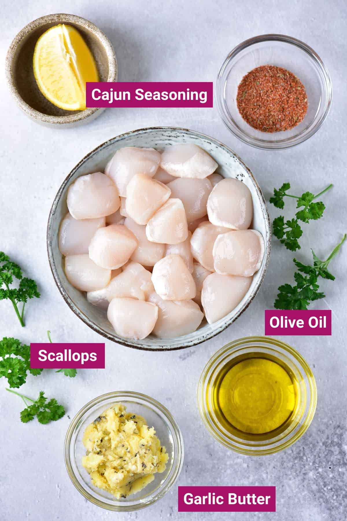 ingredients to make ninja foodi air fryer scallops cajun seasoning, scallops, garlic butter and olive oil on separate bowls