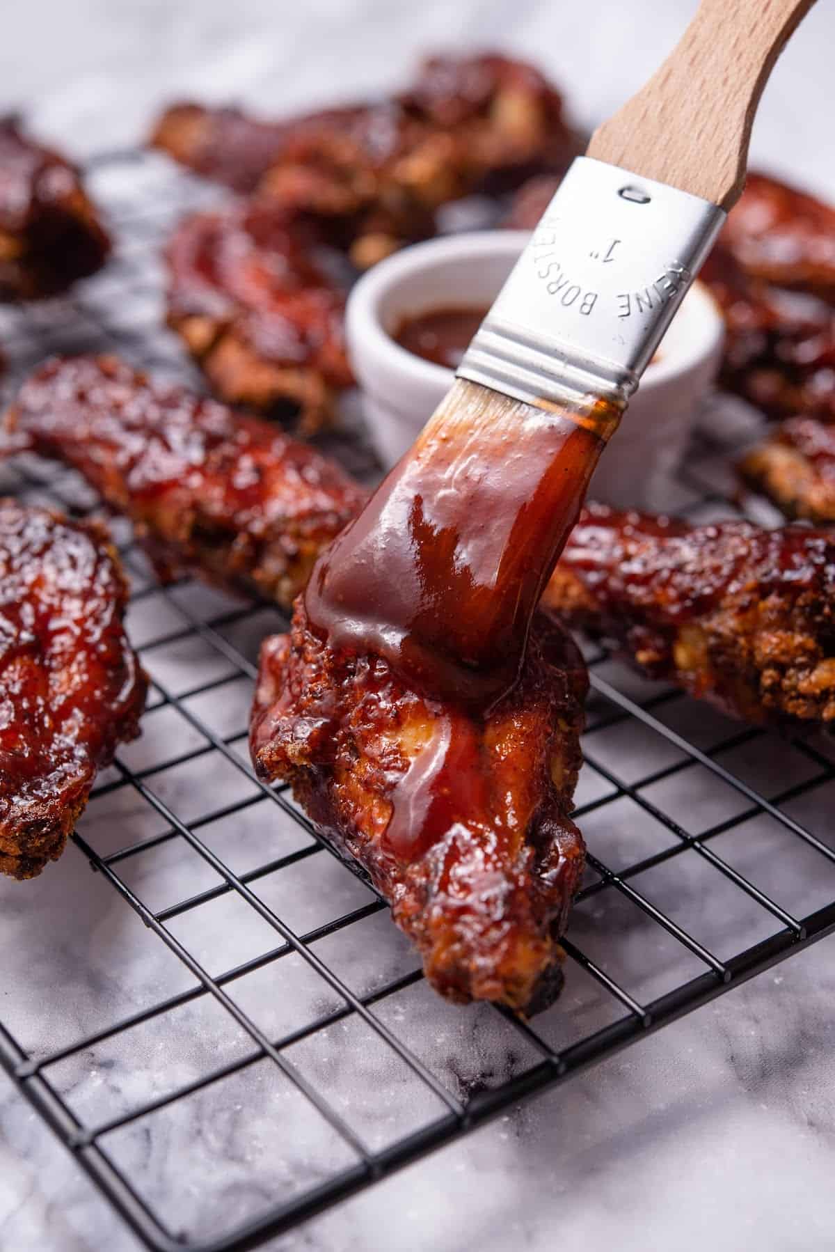 baked bbq chicken wings on a cooling rack with bbq sauce
