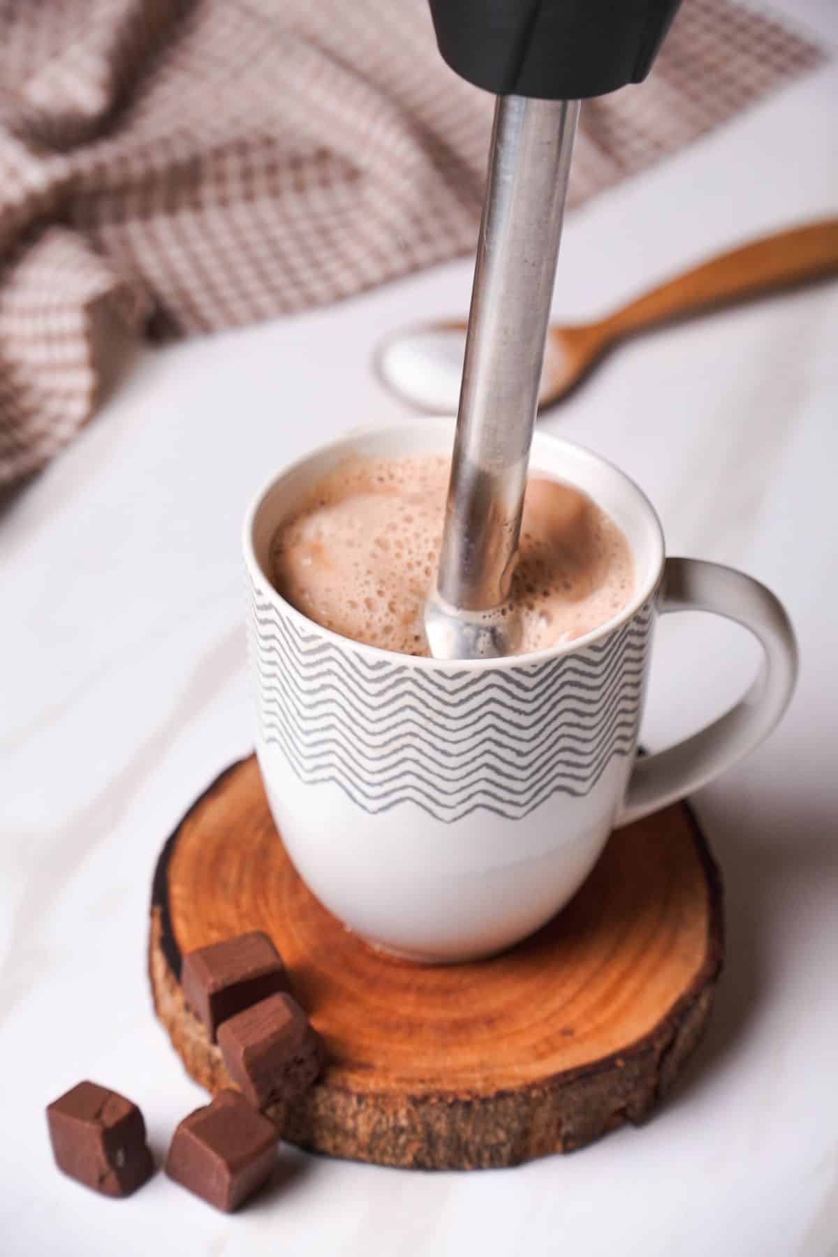 using hand blender to incorporate the milk on a mug