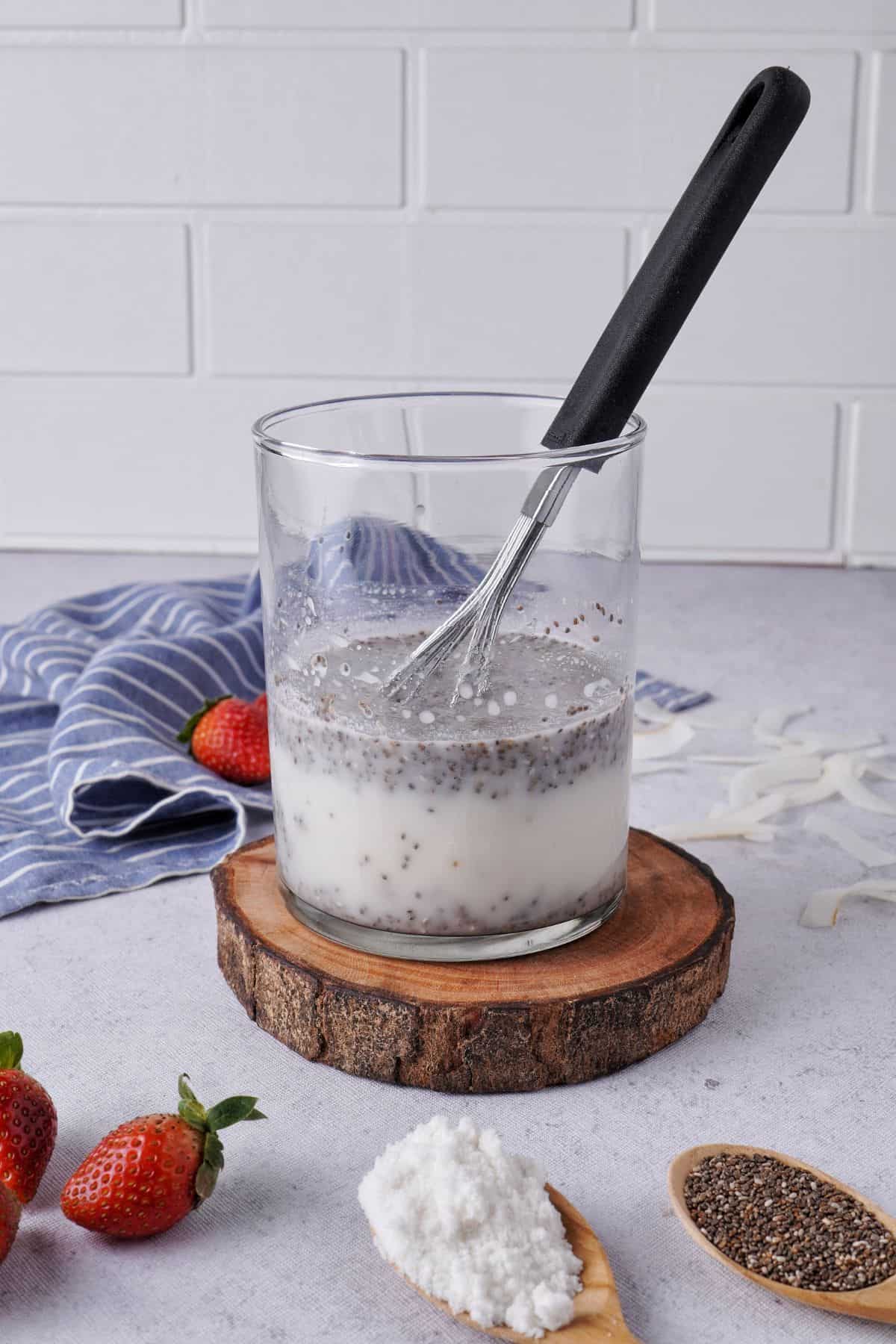 mixing black chia seeds, powdered sugar, coconut milk and vanilla extract on a jar