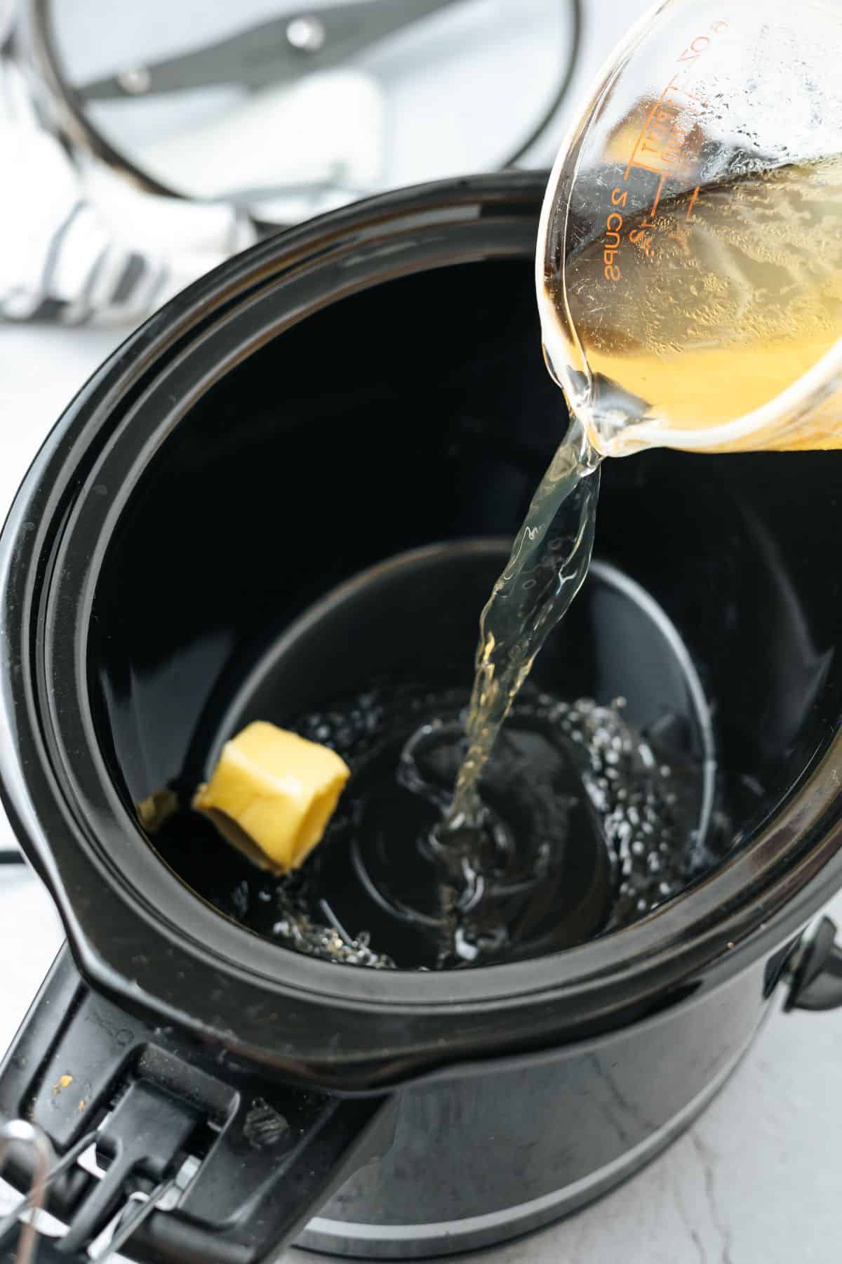 adding butter and chicken broth to the crockpot
