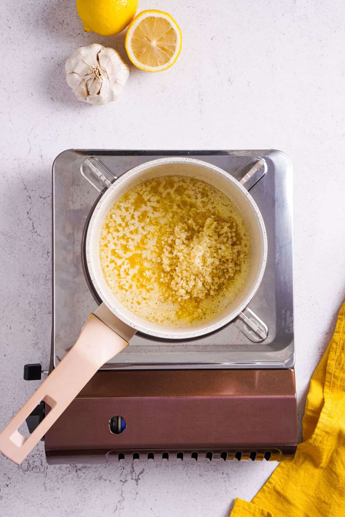 adding minced garlic to the melted butter and lemon juice on a pan