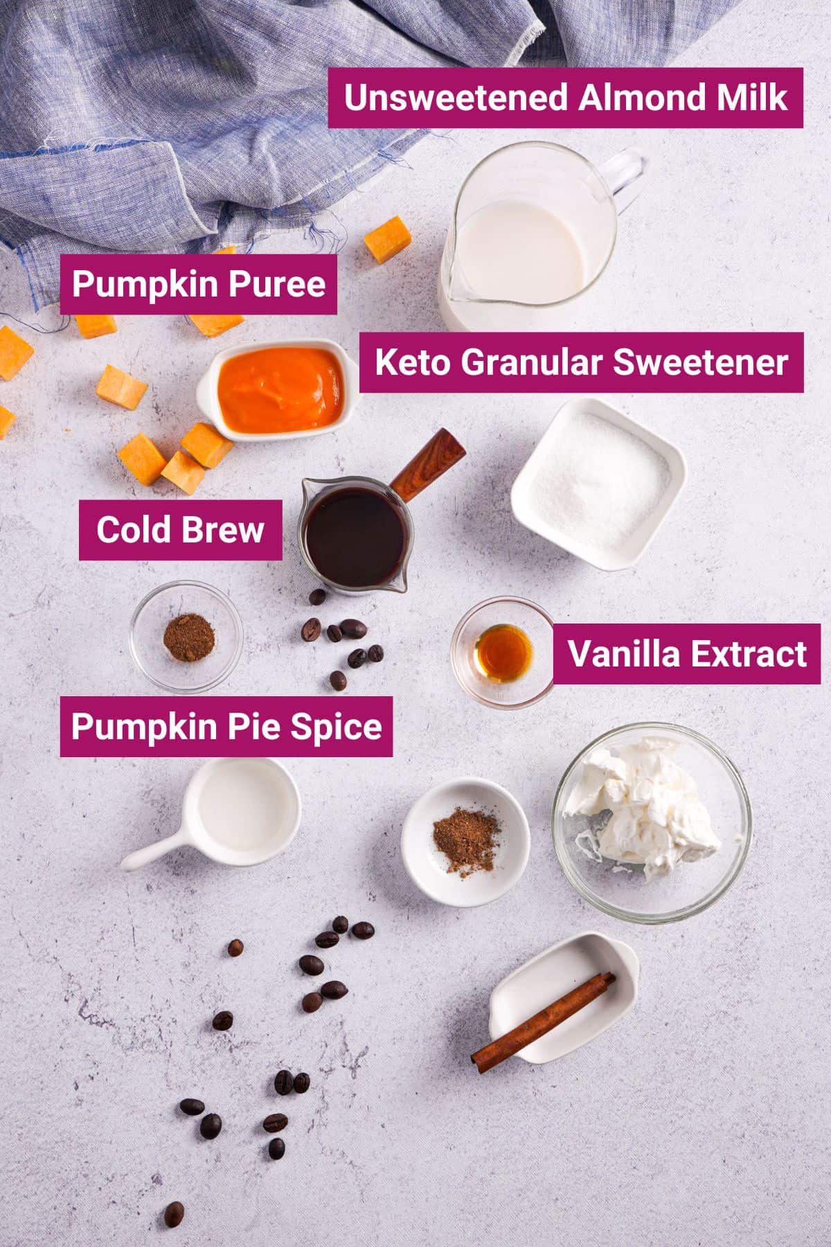 ingredients needed to make Starbucks copycat pumpkin spice latte cold brew: almond milk, pumpkin pie spice, vanilla extract, sweetener, pumpkin purée, cinnamon stick, and whipped cream on separate bowls and containers