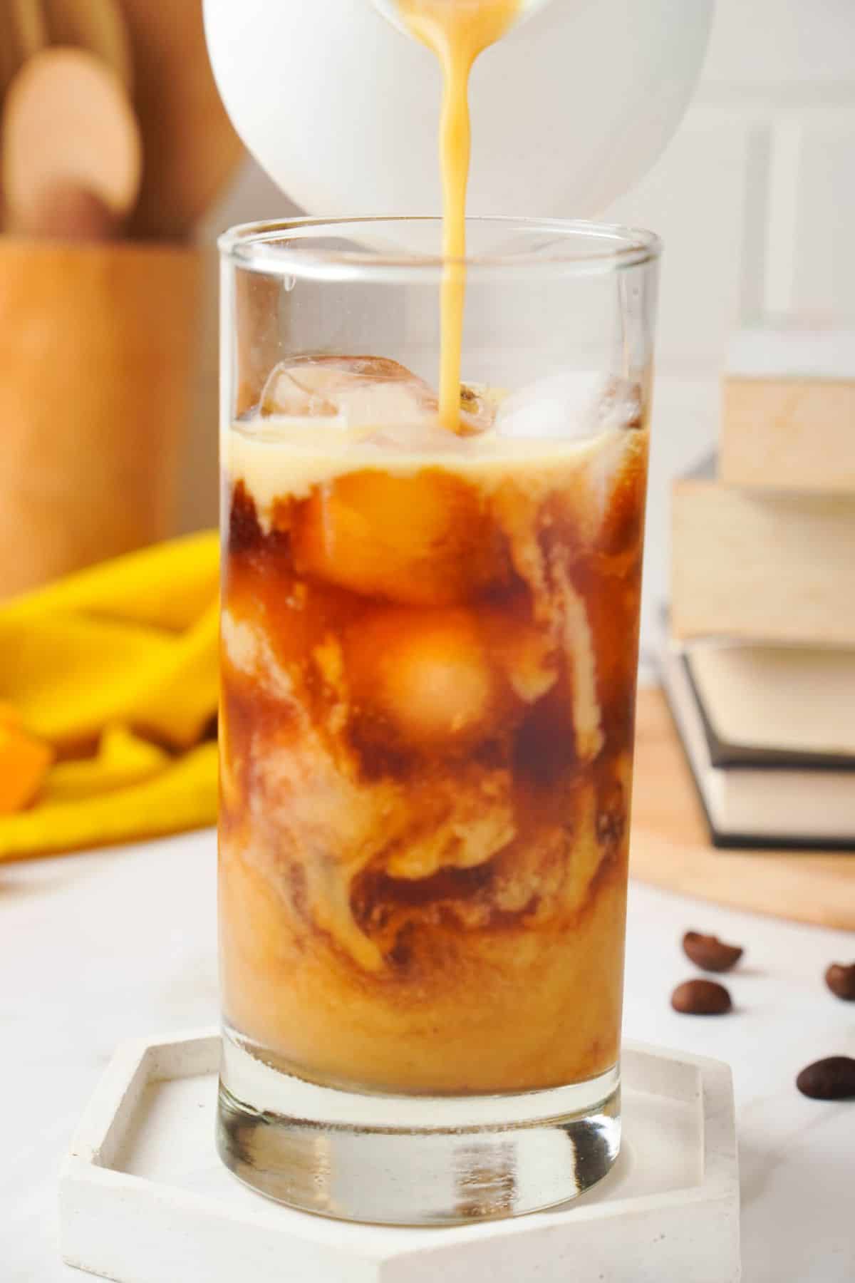 adding pumpkin cold cream to a glass of cold brew with ice