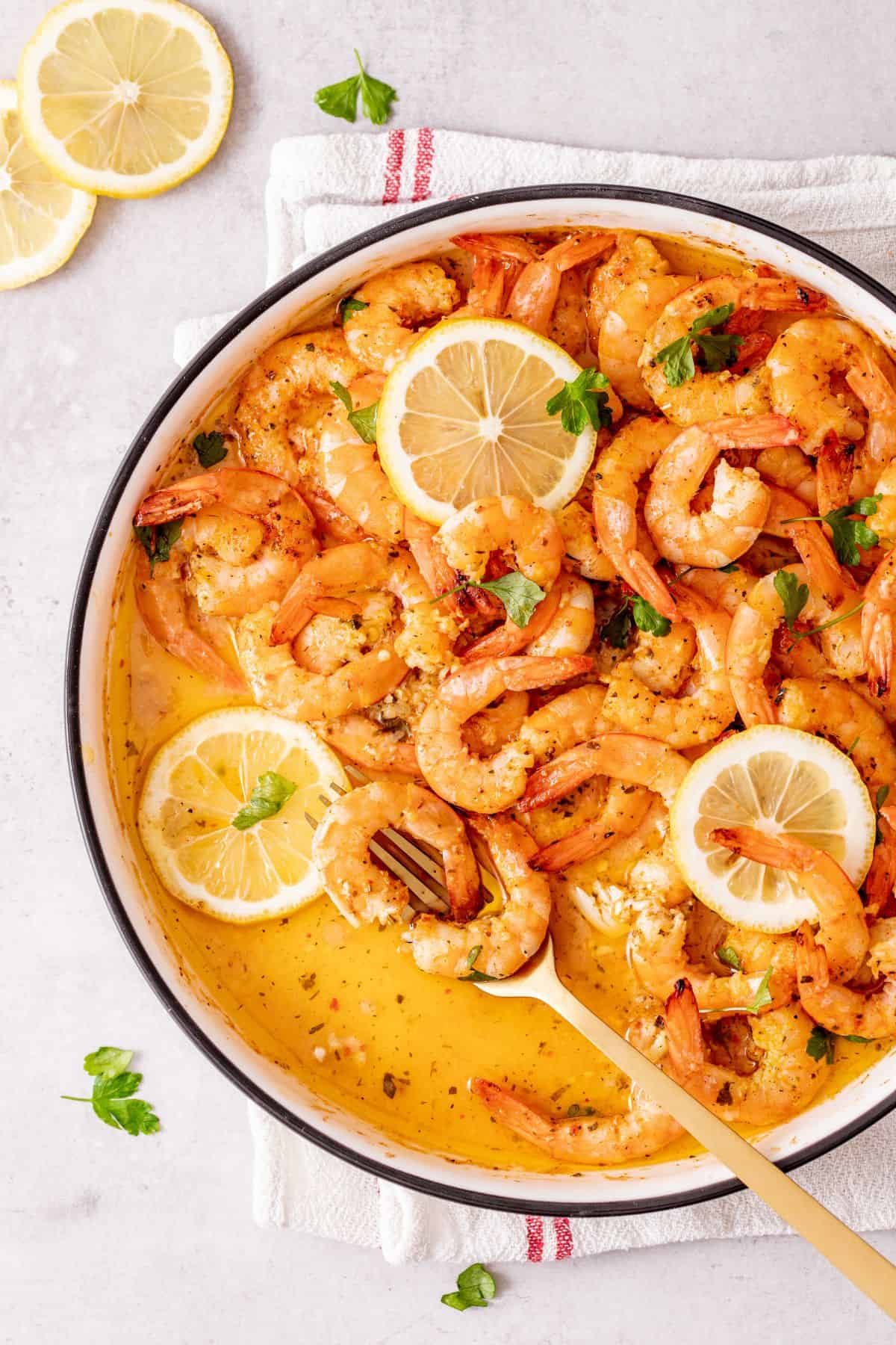baked shrimp topped with slices of lemon on a plate
