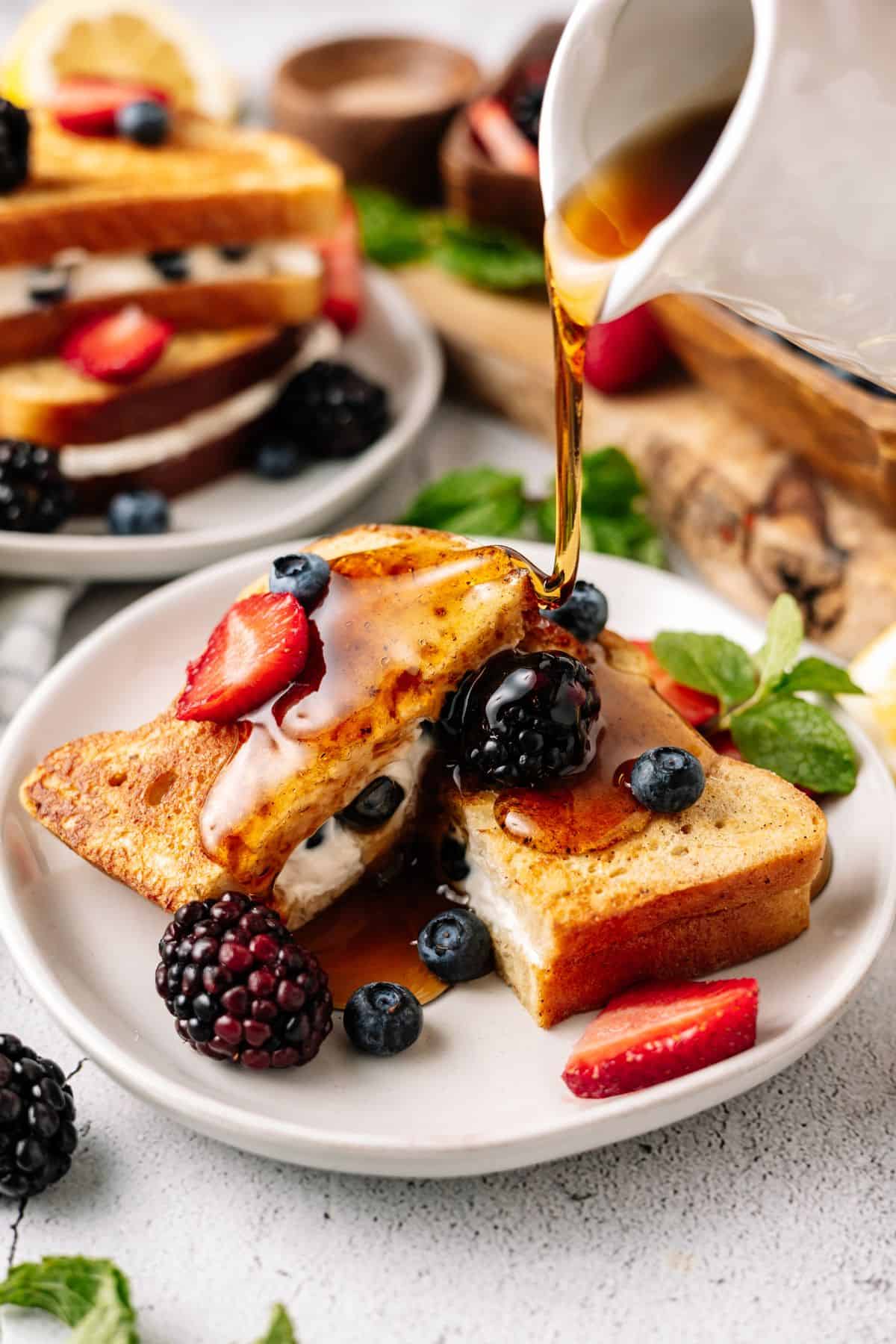 Keto French Toast stuffed with cream cheese and topped with blueberries, strawberries and maple syrup