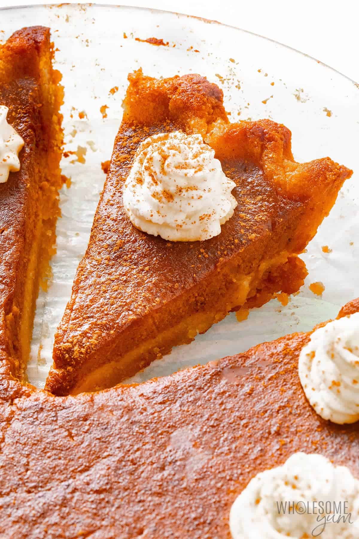 keto pumpkin pie sliced in a pie plate topped with whipped cream