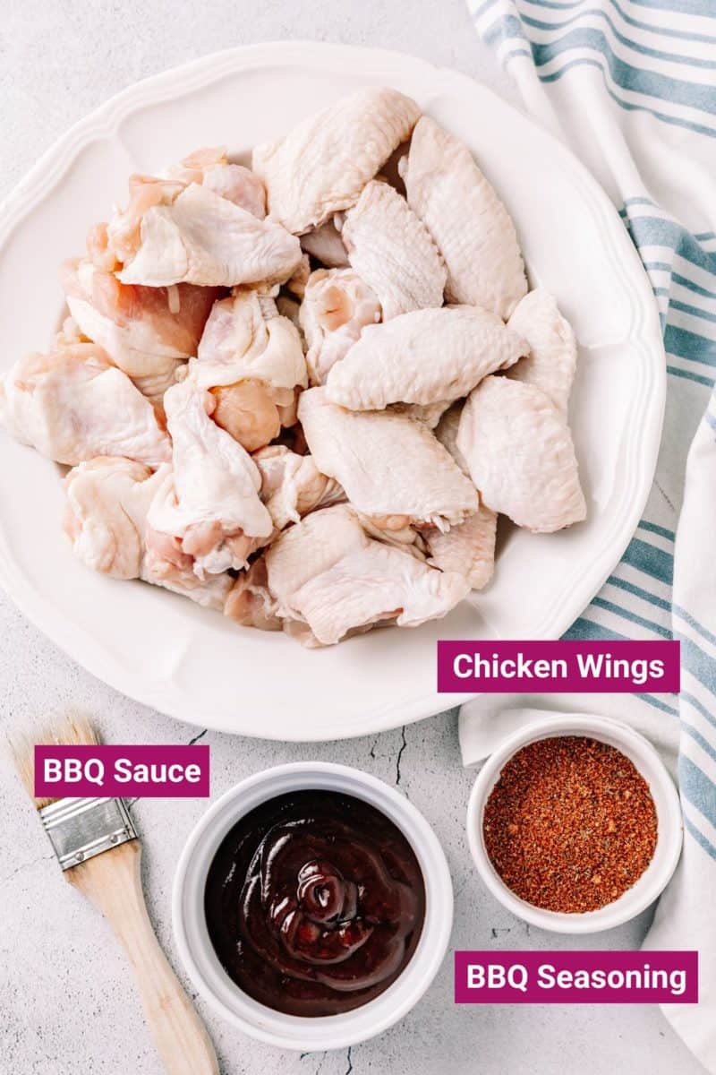 bbq seasoning, bbq sauce on separate containers and a bunch of chicken wings on a plate