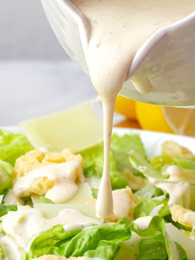 pouring Creamy Caesar Salad Dressing to the chicken and lettuce