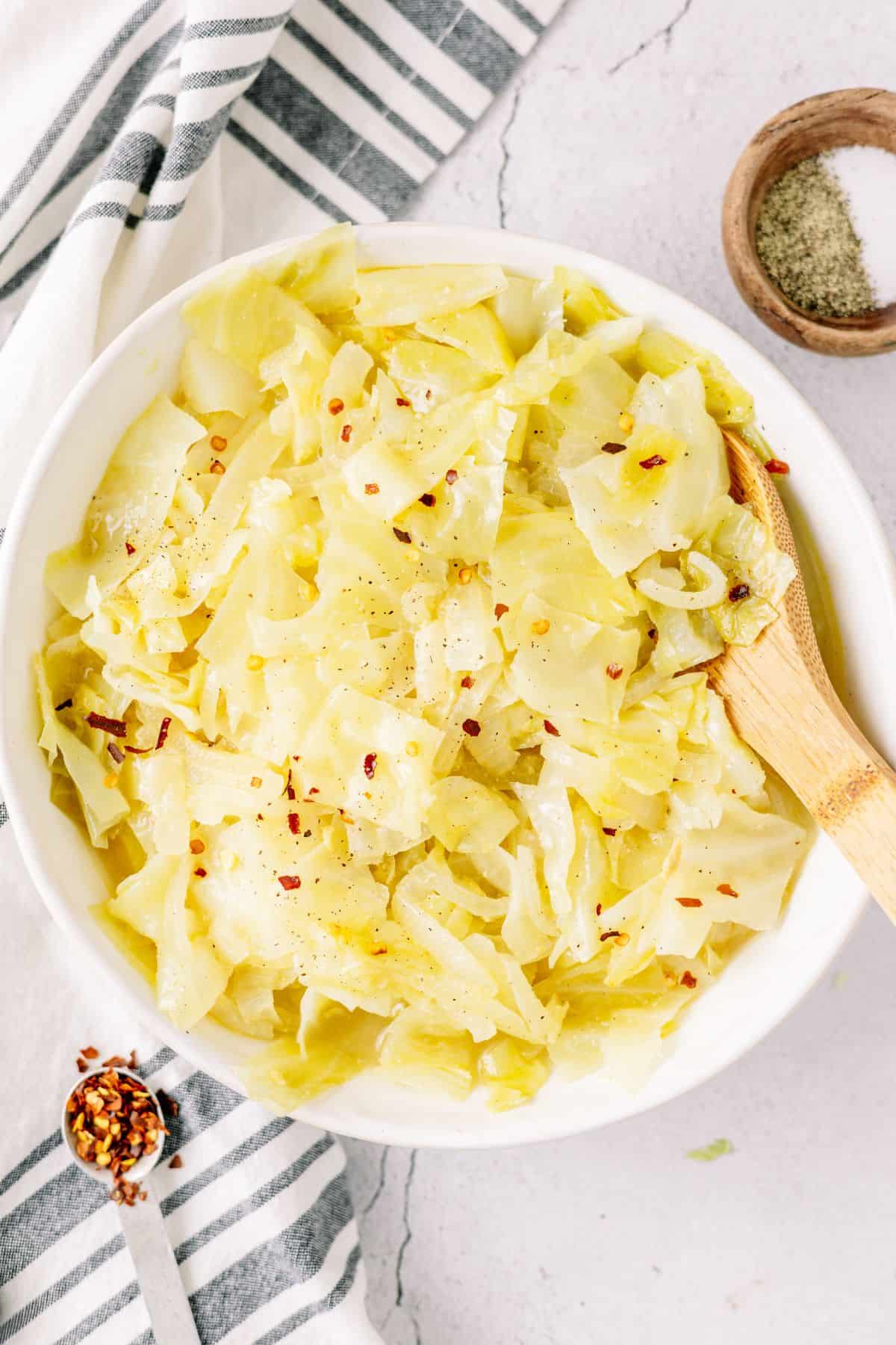 Pressure Cooker cooked Cabbage topped with red pepper flakes, sea salt and black pepper in a large white bowl