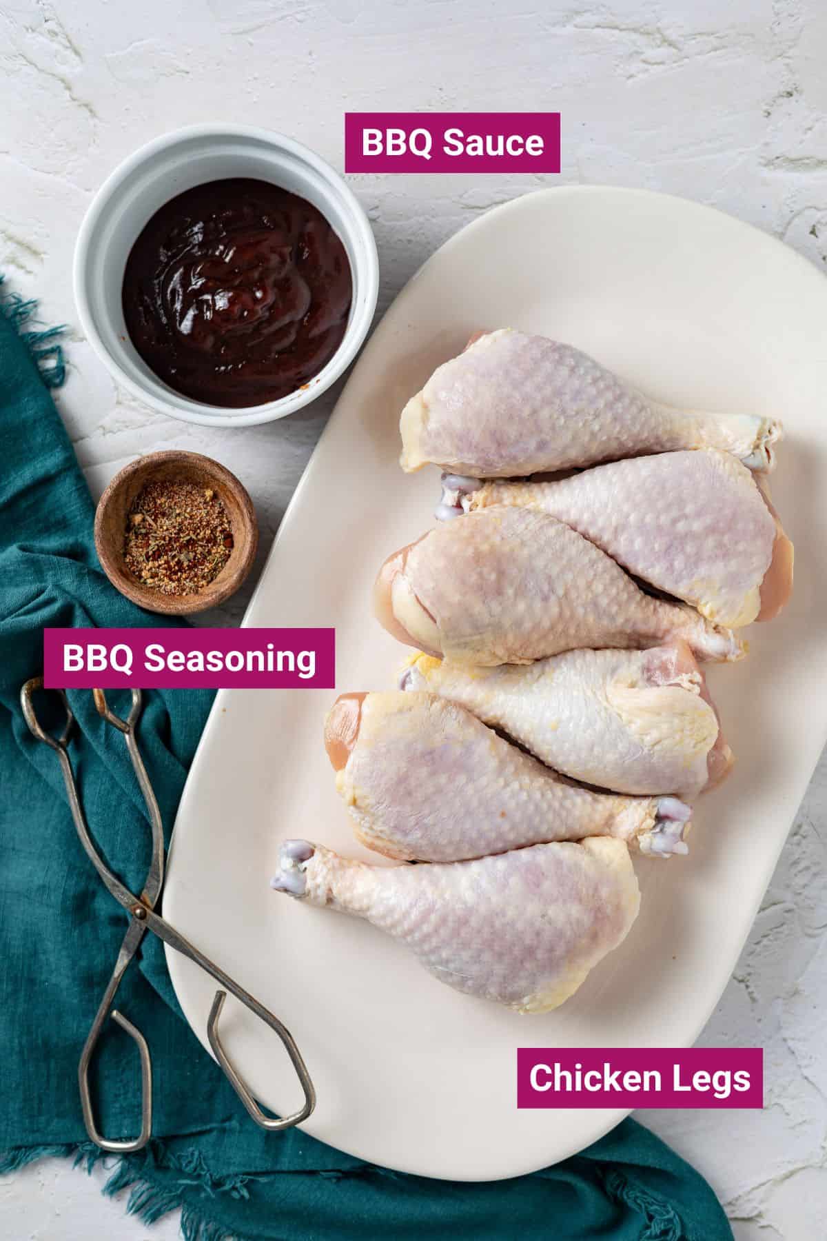 bbq sauce & bbq seasoning on separate bowls and chicken legs on a large plate