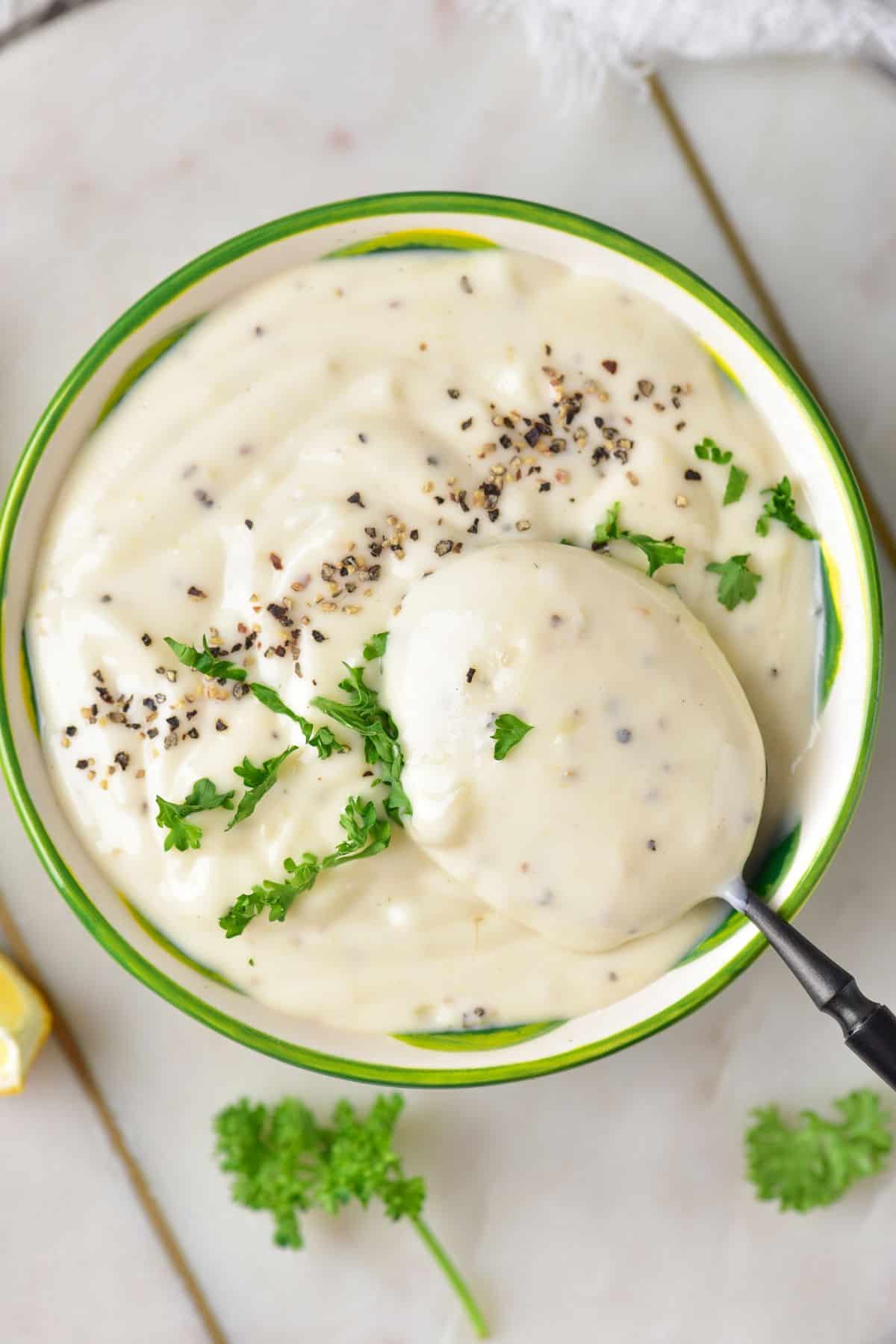 Lemon Garlic Aioli topped with parsley on a beautiful green bowl