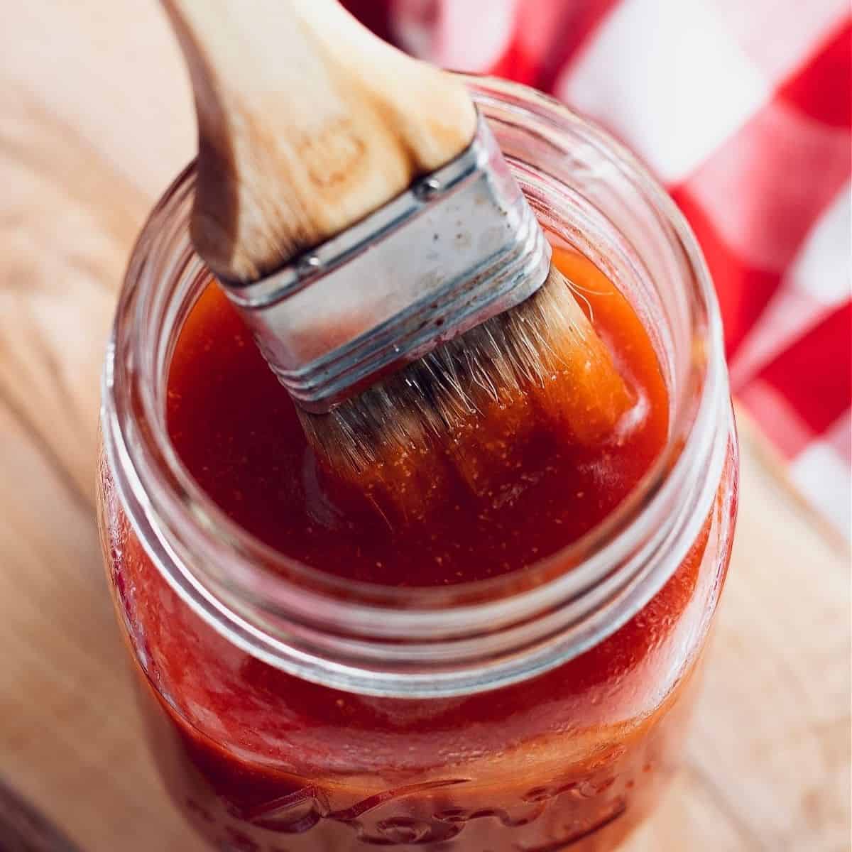 the best keto bbq sauce recipe in a glass jar with a basting bbq brush